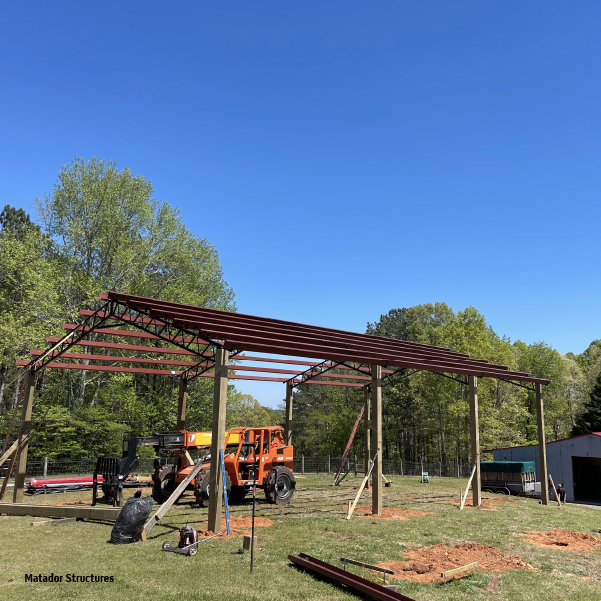 A grassy area of property is being prepared for pole barn installation and setup.